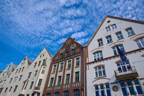 Row of historic Hanseatic houses with striking facades under a clear blue sky, Bryggen, Bergen,
