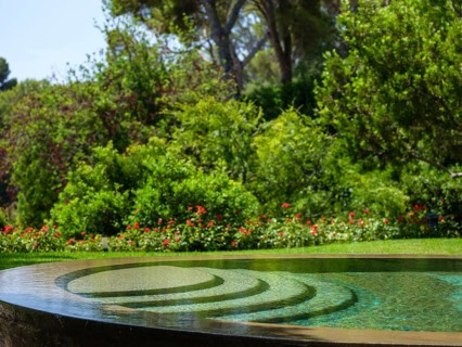 Relaxing circular pool reflecting a beautiful green garden with red flowers, perfect for a summer