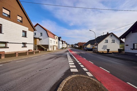 Residential building, trees, cycle path, roadway, blue sky with cumulus clouds, intersection of
