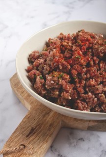 Raw minced meat, marinated with spices and herbs, in a bowl, minced meat with spices, top view,