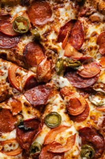 Close-up view of a mouth-watering pepperoni pizza loaded with cheese, sliced peppers, and onions,