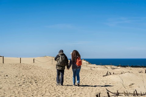 A couple of backpacker tourists travel through the sand dunes on the shores of the Baltic Sea, A