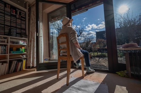 Woman wearing hat sunbathing with patio door open, Bavaria, Germany