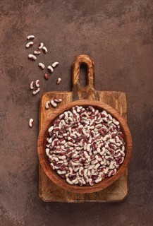 Variegated beans, red with white spots, raw in a wooden bowl, top view, no people