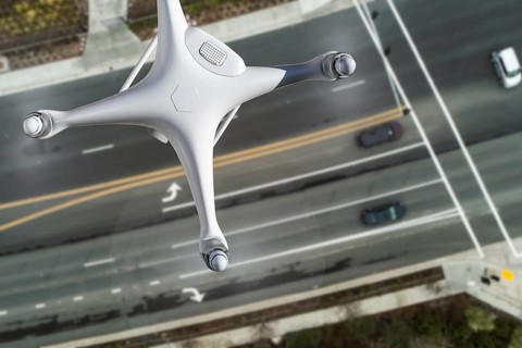 Unmanned Aircraft System Quadcopter Drone In The Air Over Roadway with Automobiles