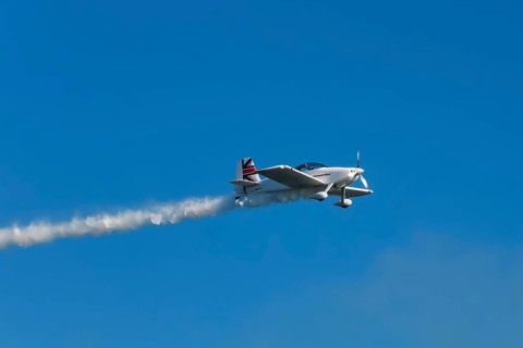 Stunt aerobatic plane performing stunts in blue sky with smoke trail. Concept of speed, difficulty,