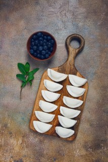 Freshly frozen dumplings with blueberries, raw, top view, no people