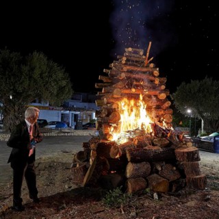 A man looks at a burning pile of wood at night, Easter fire Mayor of Psinthos, Psinthos, Holy