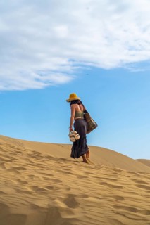 Young woman tourist walking barefoot carrying sandals on the maspalomas dunes in gran canaria,