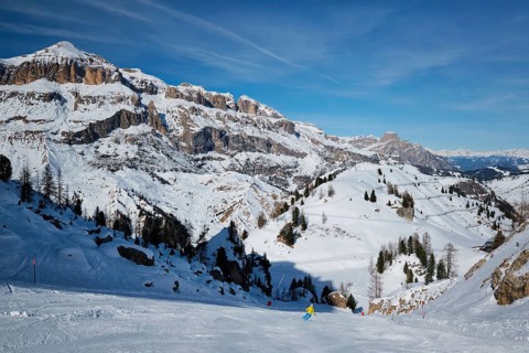 View of a ski resort piste with people skiing in Dolomites in Italy. Ski area Arabba. Arabba, Italy