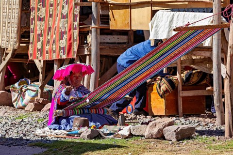 Woman weaving traditionally in Peru surrounded by colorful fabrics and craftsmanship, Elderly