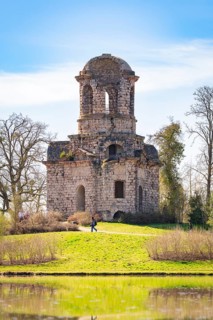 Historic tower surrounded by green nature under a blue sky, Schwetzingen Palace Gardens, Germany