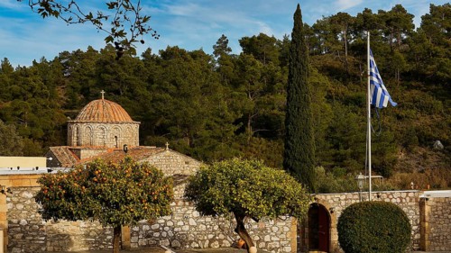 Stone church with Greek flag and cypress in the foreground, Thari Monastery, Moni Thari, near