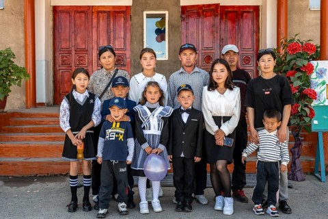 Family and school children, group posing in front of the school on the first day of school,