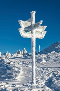 Signpost covered by snow and ice on the hiking trail on the Brocken Summit, Harz National Park,