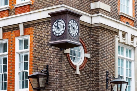 A projecting double faced clock decorates the red brick corner of the Great Scotland Yard Hotel,