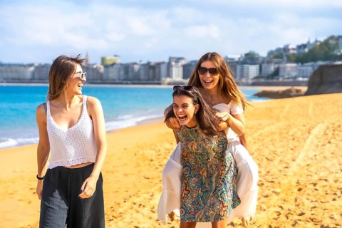Three friends spending summer vacation together, two women sharing a joyful piggyback ride on the