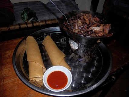 A tray of injera and wot, a meat dish and a bowl of chili sauce, Ethiopia