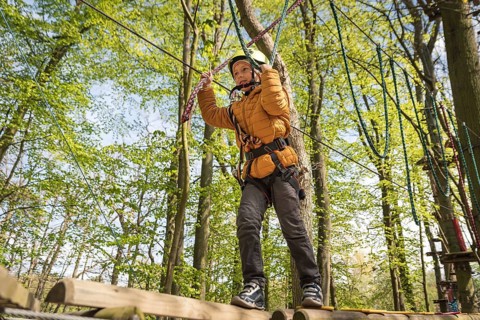 Portrait of cute little boy walk on a rope bridge in an adventure rope park