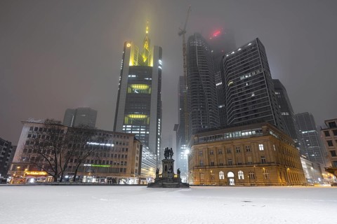 Snow lies on the Rossmarkt in Frankfurt am Main. Most of the office lights in the skyscrapers of