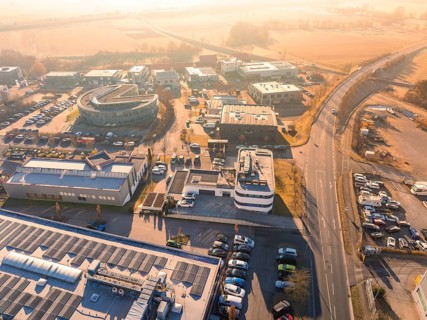 Bird's eye view of industrial plants and roads in sunny weather with surrounding landscape,