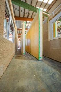 A narrow corridor between tall wooden panels in a new building on a construction site, façade