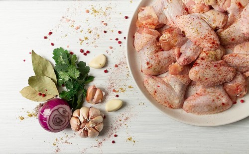 Fresh, raw chicken wings, with spices, on a white wooden table