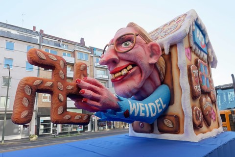 Alice Weidel from the AfD as a Nazi witch, holding gingerbread in the shape of a hook, papier-mâché