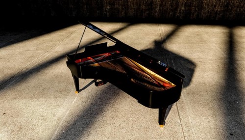 A grand piano is positioned elegantly on a concrete floor, bathed in sunlight. The light creates