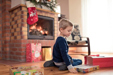 5 years old boy in front of the fireplace is happy with Christmas gifts in Tymowa, Poland