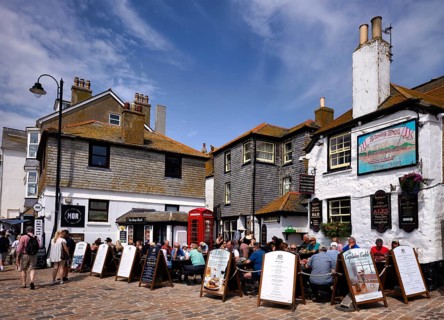 People, tourists, sit on the terrace of the Sloop Inn, one of Cornwall's oldest inns, St Ives,
