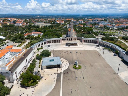 Wide view of a city with basilica and large square, many people, blue sky and clouds, aerial view,