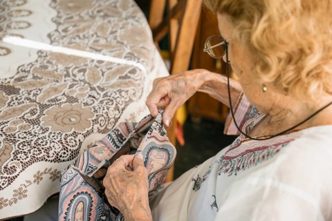 Senior seamstress carefully stitching fabric, demonstrating expertise and focus in dressmaking,
