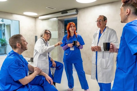 Group of diverse medical professionals, including doctors and nurses, enjoying a coffee break while
