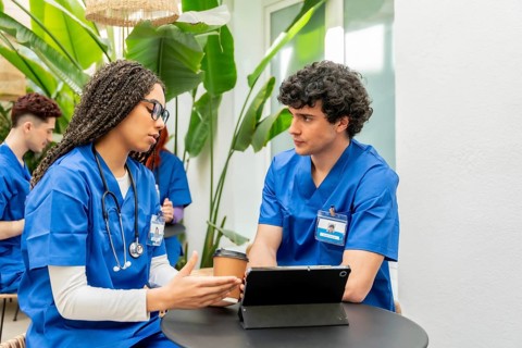 Young medical students wearing blue scrubs and stethoscopes are collaborating on healthcare