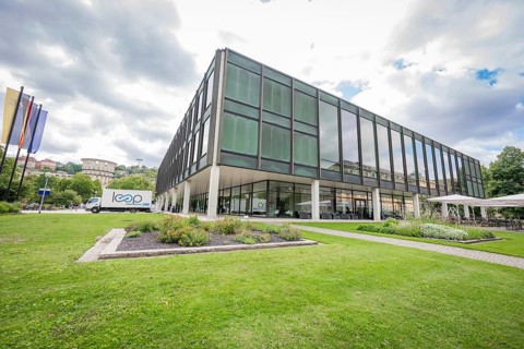 Green grass area in front of a modern building with glass façade, state parliament of