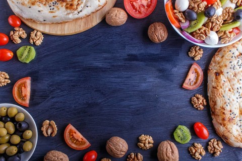 Frame made from cherry tomatoes, mozzarella cheese, olives, kiwi, onion and walnuts on black wooden