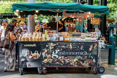 A mobile Gastronomica market cart advertising cannoli and sweet truffles displays trays of Italian