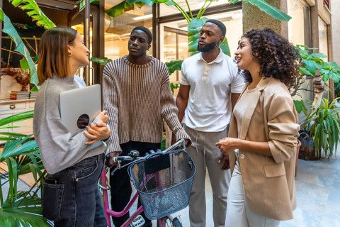 African man arriving at the office with bike talking with coworkers in the entrance