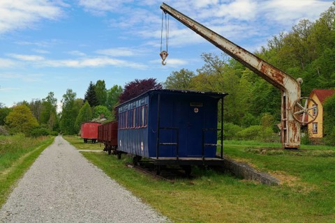 Abandoned train wagon on a rail with an old crane in rural area, cycle route, Banevallsleden,