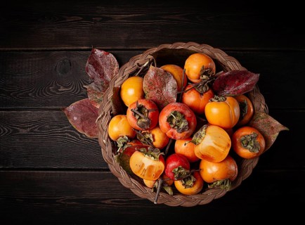 Fresh persimmon in a basket, with leaves, top view, no people