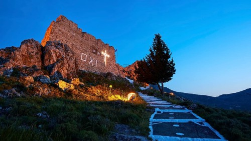 Night shot of a castle ruin with illuminated cross and tree, quiet and historical atmosphere,