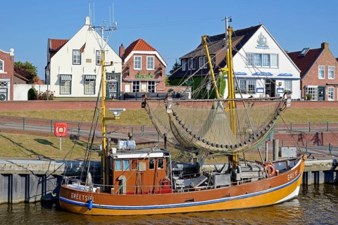 Crab cutter in the harbour in front of historic buildings, blue sky, Greetsiel, North Sea, Lower