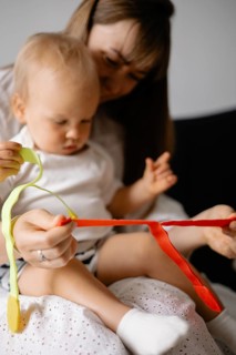 A woman and baby in white clothing play with colorful ribbons, creating an engaging and warm