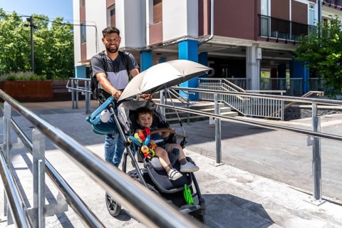 Father pushing a baby stroller with his happy son sitting inside, navigating an urban environment