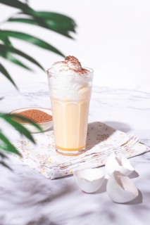Eggnog drink, egg yolk, in a glass, with cream and cinnamon, sunlight