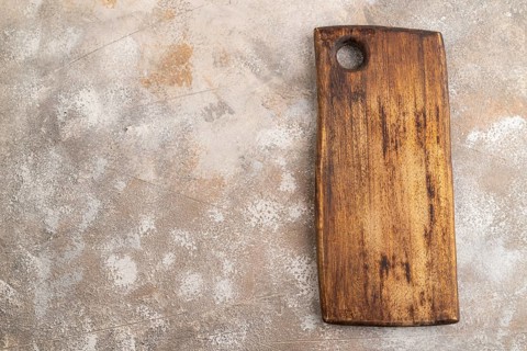 Empty rectangular wooden cutting board on brown concrete background. Top view, copy space, flat lay