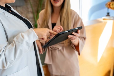 Healthcare professional in lab coat pointing at tablet screen, explaining treatment options to a