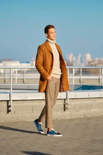 Spring, autumn outfit. Street fashion. Young man in checkered trousers, sweater and wool coat