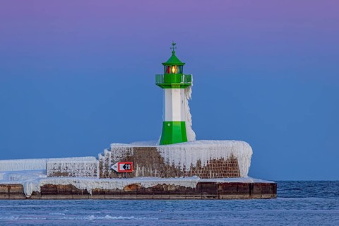 Ice covered Molenfeuer, frozen lighthouse, pier light on mole in the harbour of Sassnitz in winter,